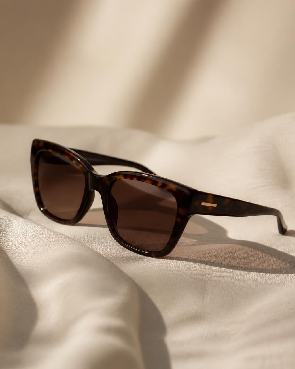 Designer sunglasses styled in an editorial composition on a light background